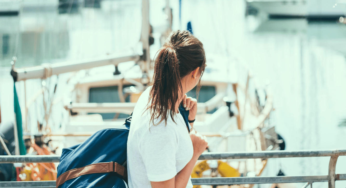 Young woman looking out at a harbor of boats.